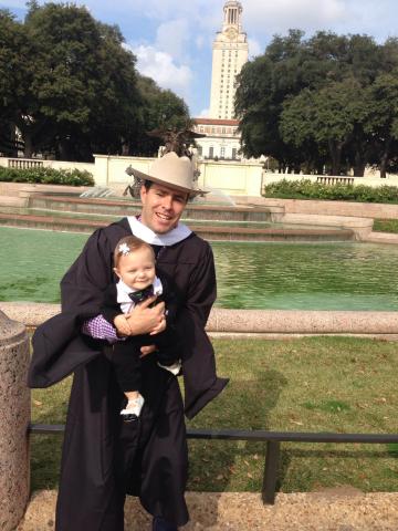 Joey Williams with baby in front of tower and fountain