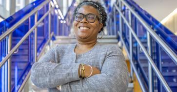 Natalie T. J. Tindall, Ph.D., in front of a staircase standing with her arms crossed
