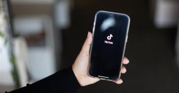 Hand holding out a smartphone with the TikTok logo displayed