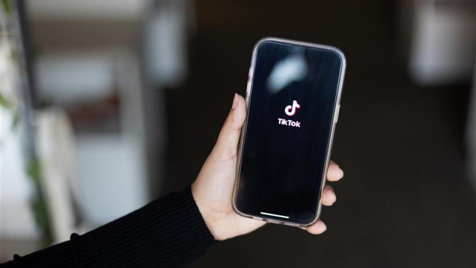 Hand holding out a smartphone with the TikTok logo displayed