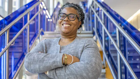 Natalie T. J. Tindall, Ph.D., in front of a staircase standing with her arms crossed