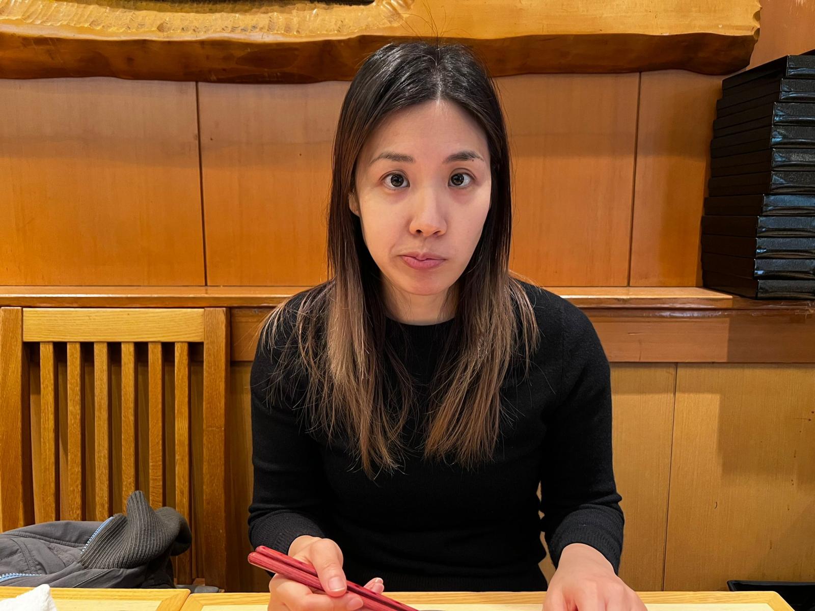 Sieun Ha sitting at a table holding chopsticks