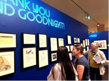 students looking at wall exhibit with docent